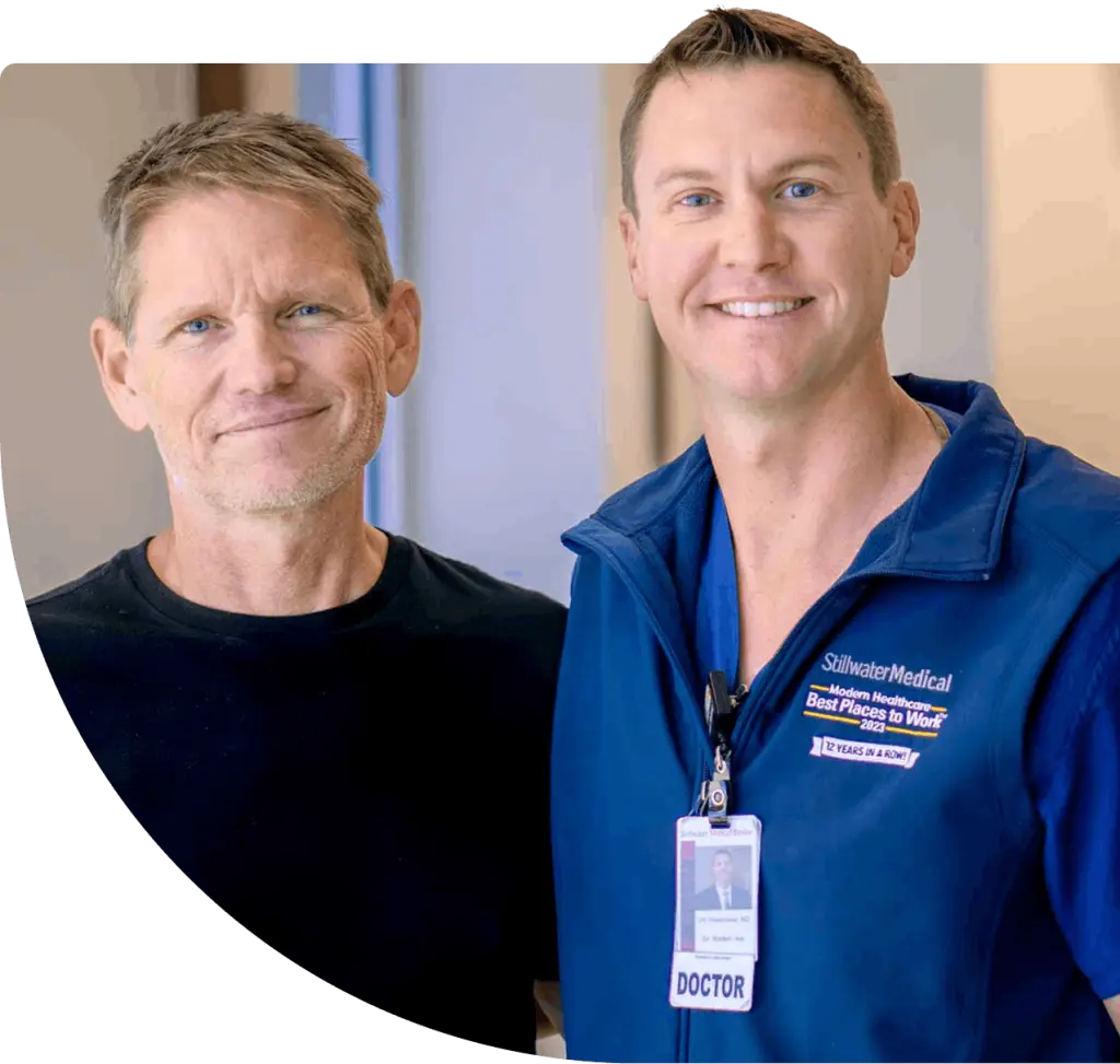 Two Stillwater Medical Center surgeons stand side by side smiling at the camera